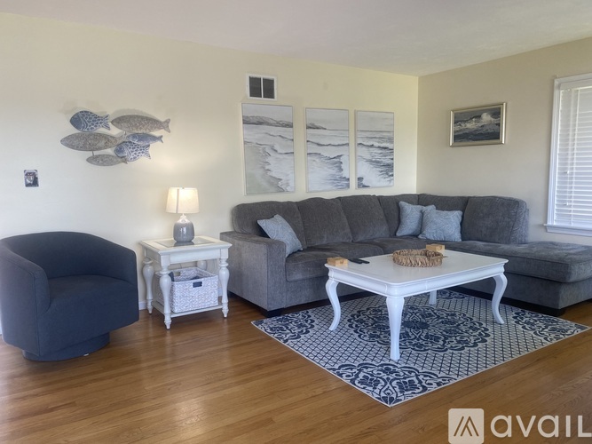 A living room with a grey couch, a white end table, and a blue chair.