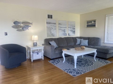 A living room with a grey couch, a white end table, and a blue chair.