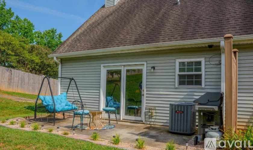 A house with a blue chair and a swing set in the yard.