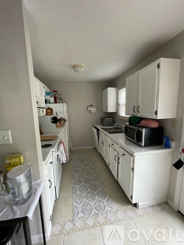 A kitchen with white cabinets and a black fridge.