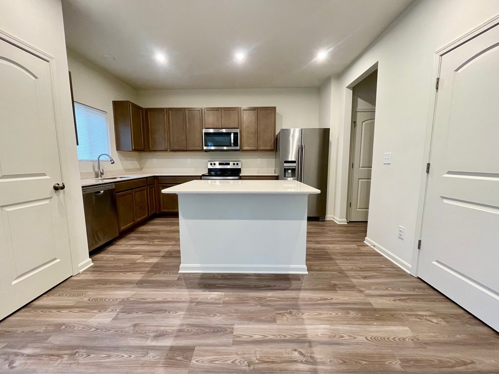 A kitchen with a white island in the middle of a room with brown tiles.