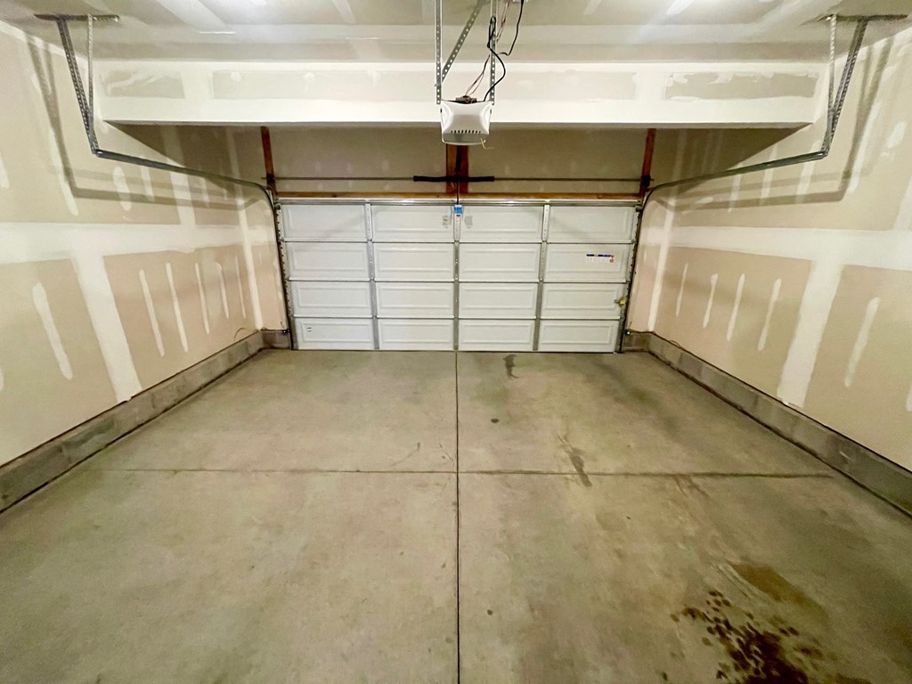 A garage with a white door and a concrete floor.