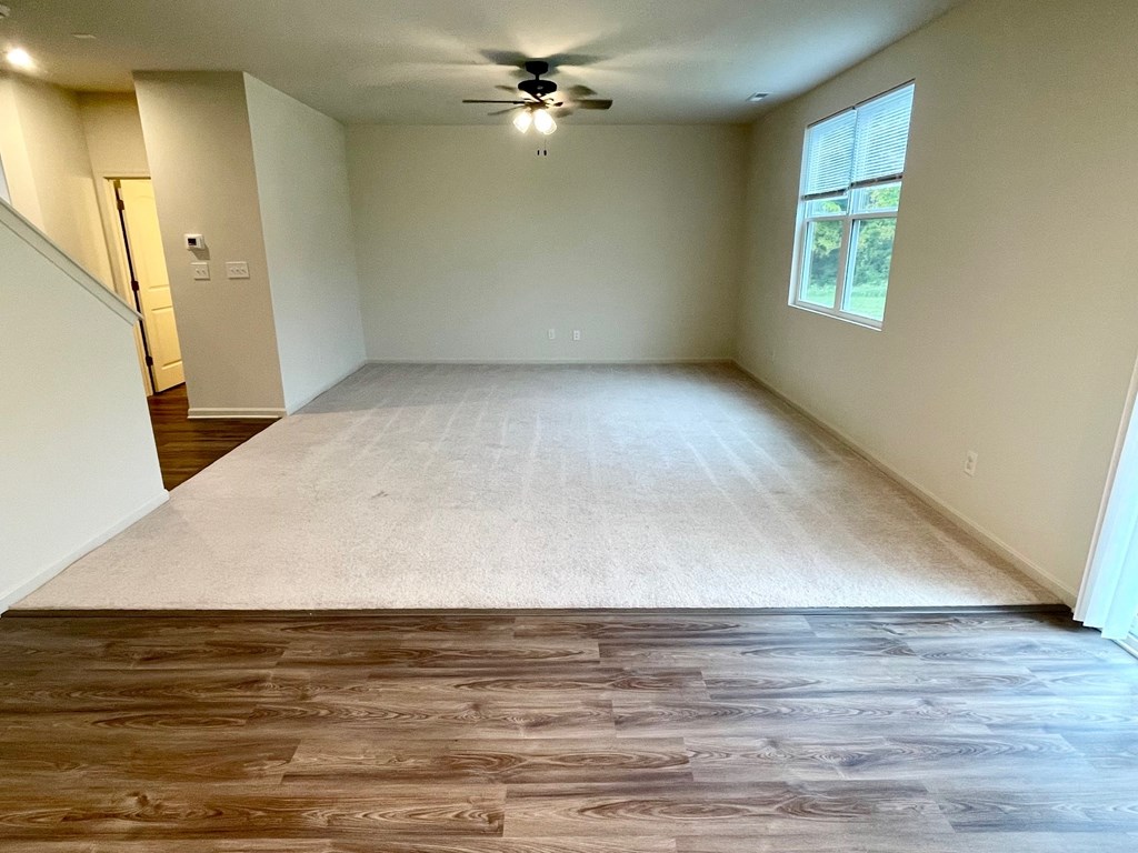 A room with a ceiling fan and a window with blinds.
