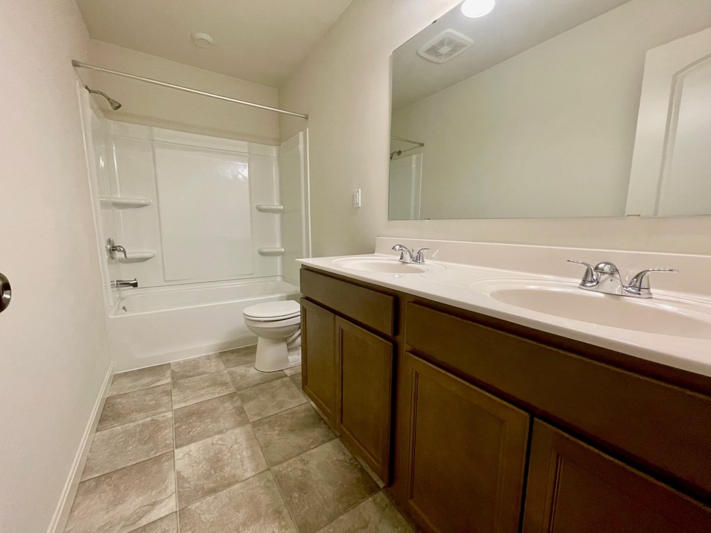 A bathroom with a toilet, sink, and mirror.