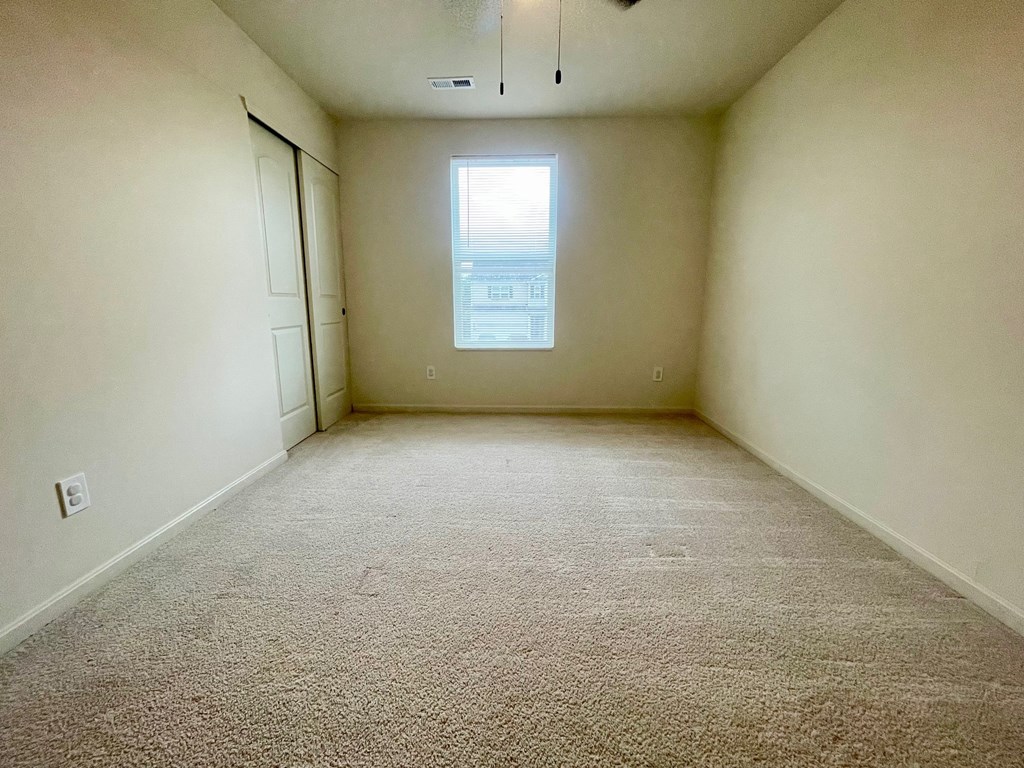 A room with a carpeted floor and a window.