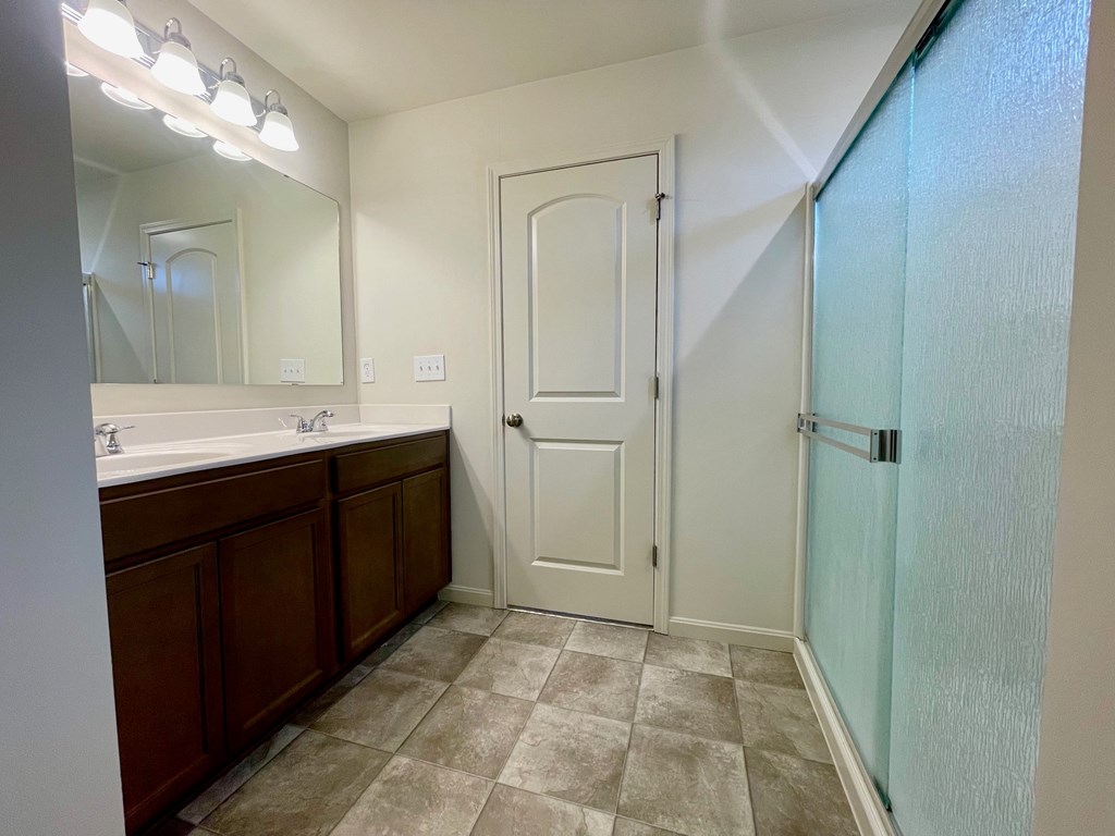 A bathroom with a white door and a tiled floor.