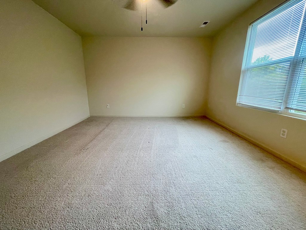 A room with a carpeted floor and a window with blinds.