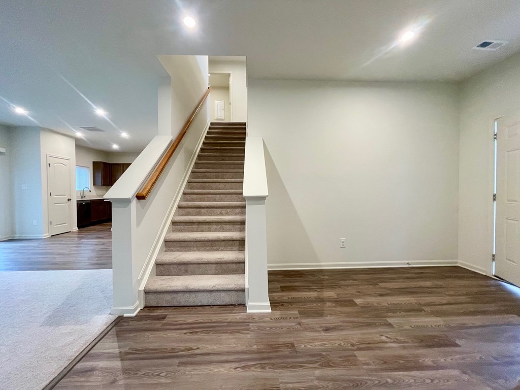 A staircase with a white railing and a beige carpeted floor.