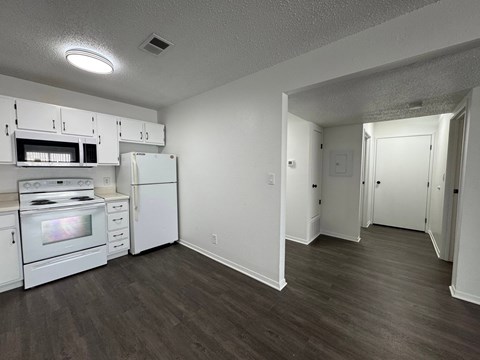 A kitchen with white appliances and wood floors.