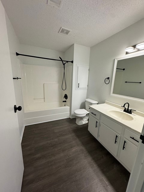 A bathroom with a toilet, sink and mirror.
