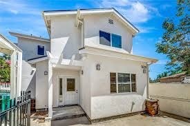 A white two-story house with a blue window on the second floor.
