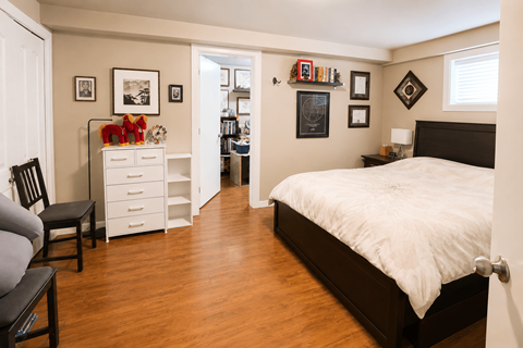 A bedroom with a white bed and a white dresser with a red object on top.