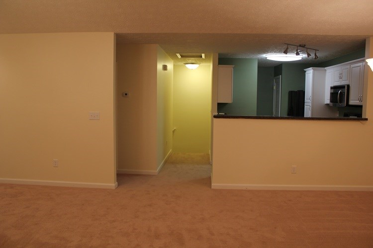 A room with a yellow door and a kitchen area.
