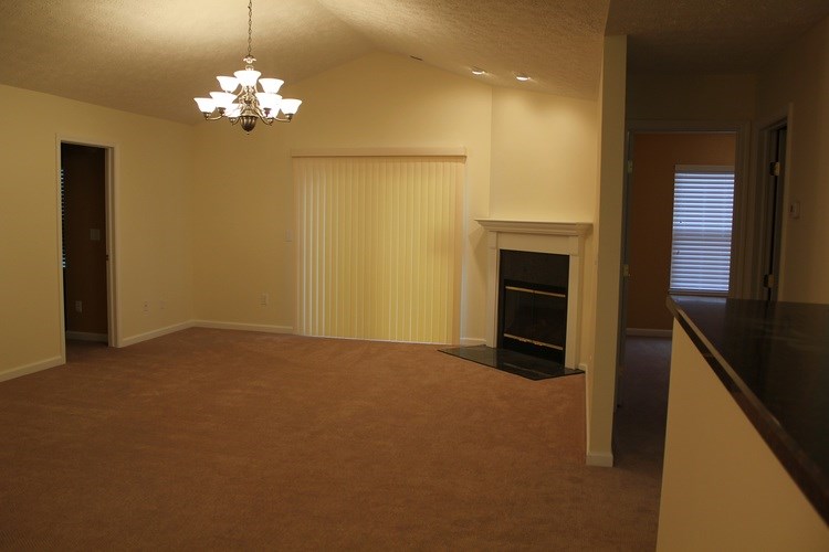 A large, empty room with a fireplace and a chandelier.