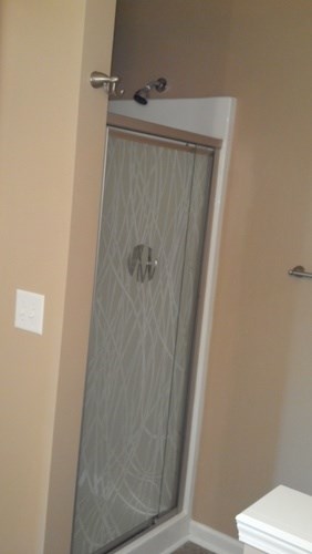 A white toilet sits next to a glass door.