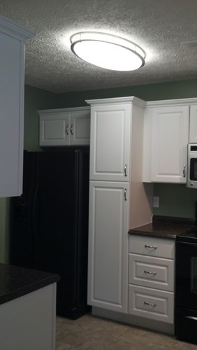 A kitchen with white cabinets and a black refrigerator.