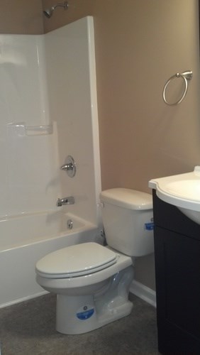 A white toilet with a blue sticker on the side sits next to a white sink.