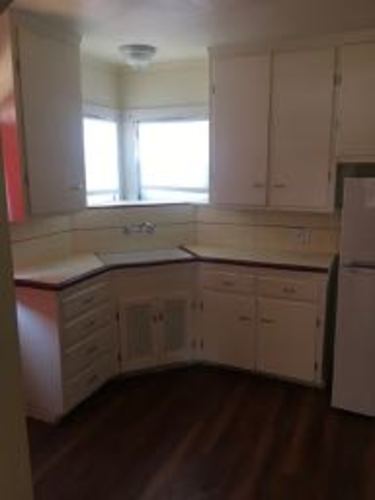 A kitchen with white cabinets and a window.