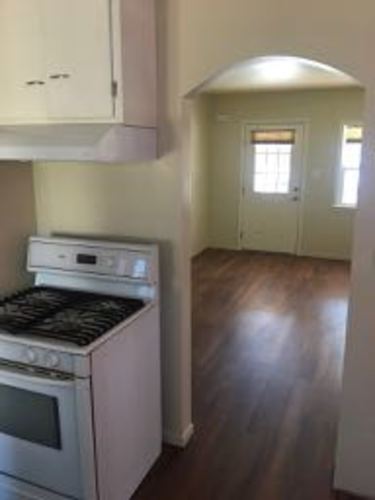 A white oven and stove top are in a kitchen with wood floors.