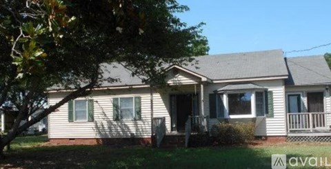 A house with a porch and a tree in front of it.
