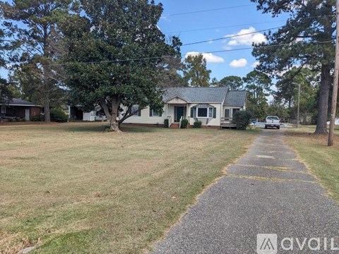 A grassy area with a walking path and trees in front of houses.