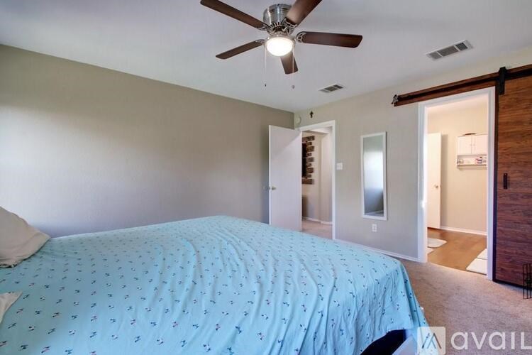 A bedroom with a bed covered in a blue bedspread with a ceiling fan above it.