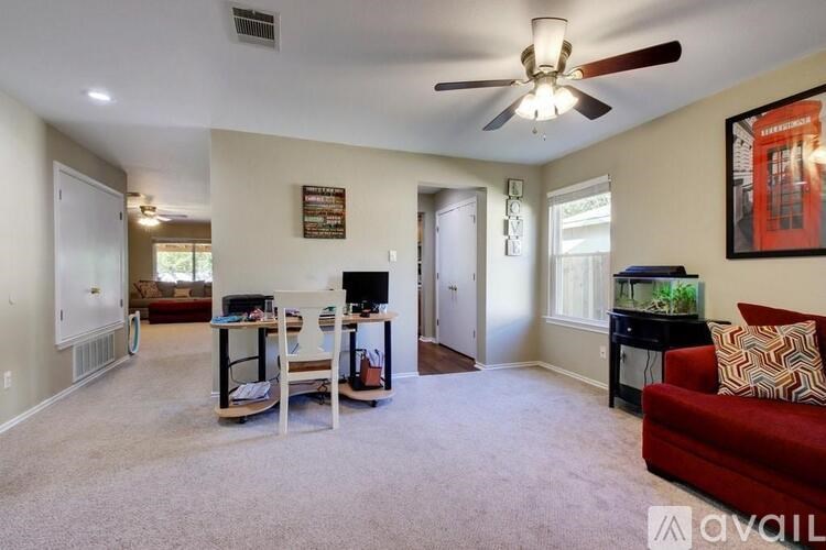 A living room with a red couch and a ceiling fan.