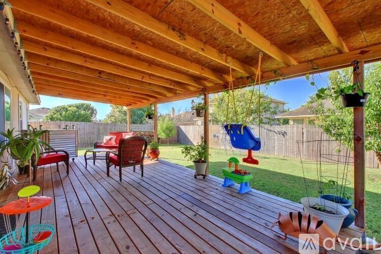 A wooden deck with a red chair and a blue swing.