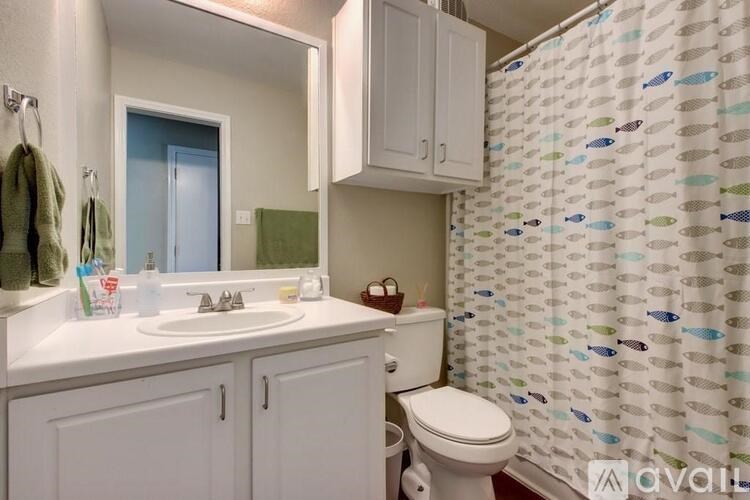 A bathroom with a white toilet, sink, and shower curtain.