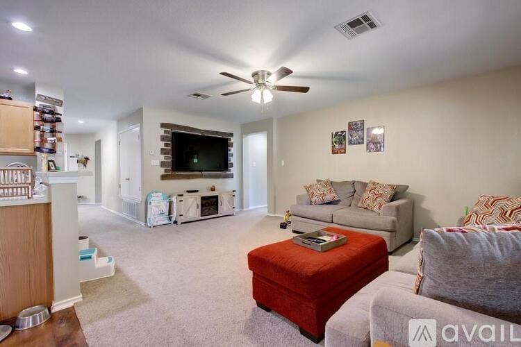 A living room with a red ottoman and a grey couch.