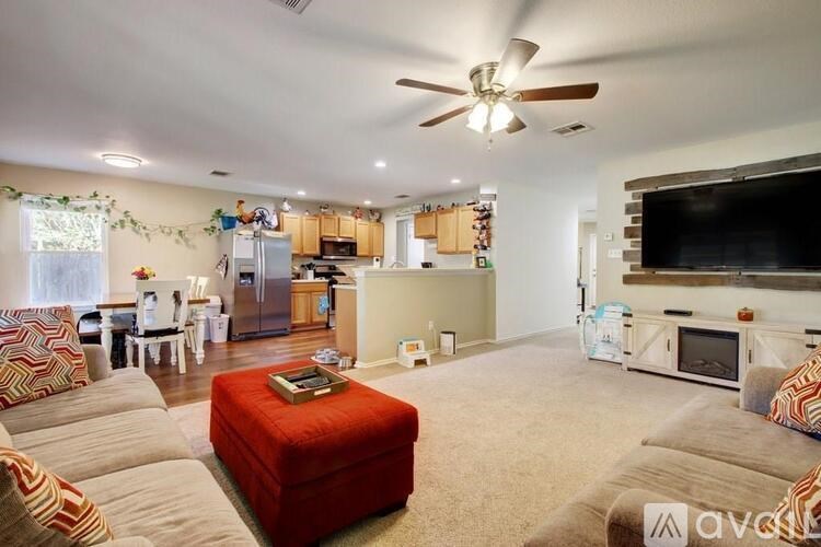 A living room with a red ottoman and a television on the wall.