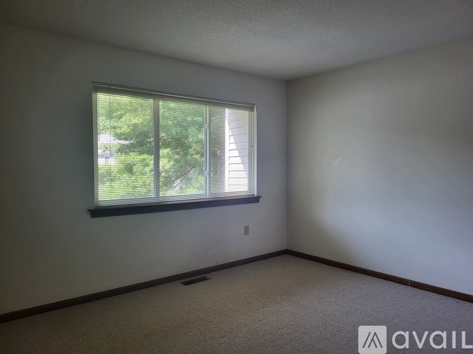 A room with a window and a carpeted floor.