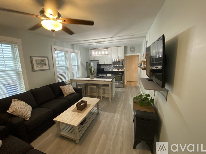 A living room with a black couch and a wooden coffee table.