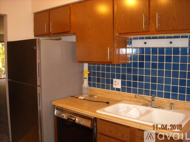 A kitchen with a black refrigerator and wooden cabinets.