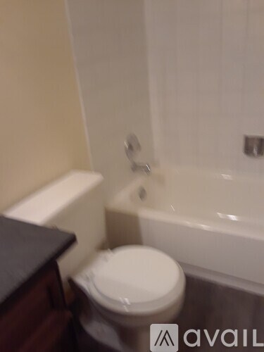 A white toilet in a small bathroom with a white bathtub.
