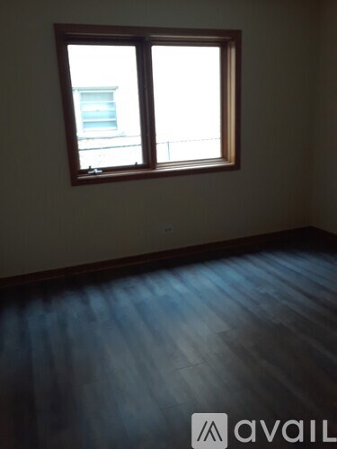 A room with a window and wooden flooring.