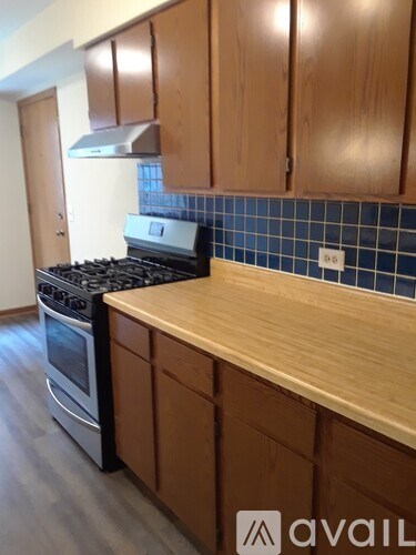 A kitchen with wooden cabinets and a blue tile backsplash.