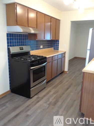 A kitchen with a black stove top oven and wooden cabinets.