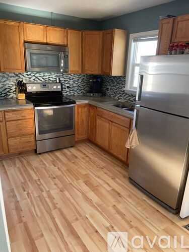 A kitchen with wooden cabinets and a stainless steel refrigerator.