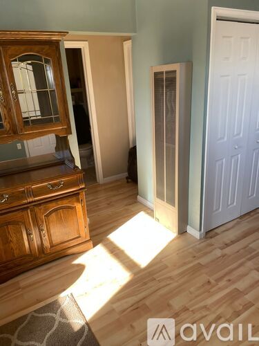 A room with a wooden dresser and a mirror on top of it.