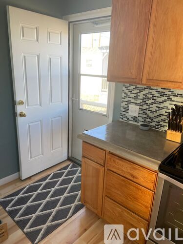 A kitchen with wooden cabinets and a black and white tiled backsplash.