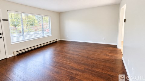 A room with wooden flooring and a window with blinds.