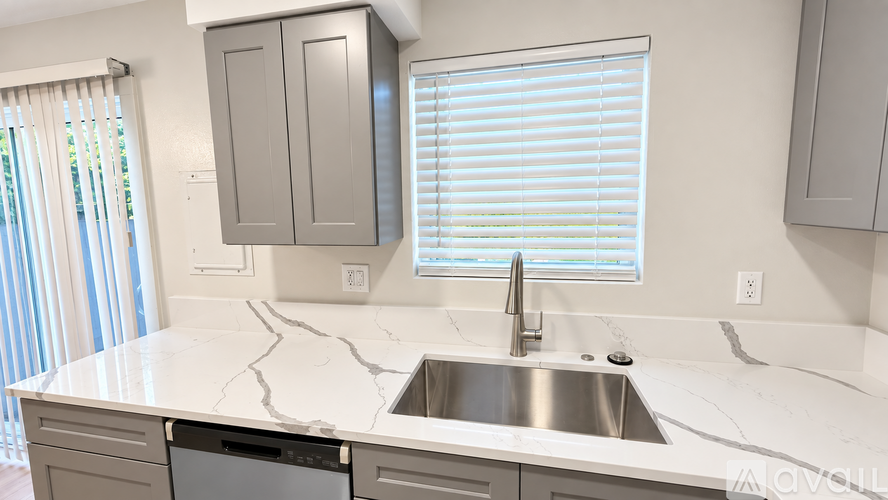 A kitchen with a stove, sink, and cabinets.