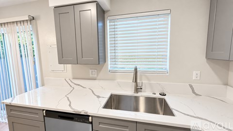A kitchen with a stove, sink, and cabinets.