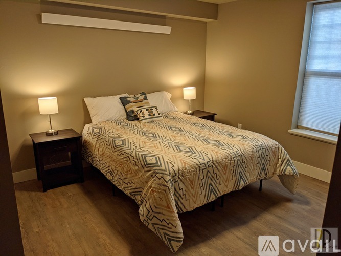 A bedroom with a bed, two lamps, and a window.