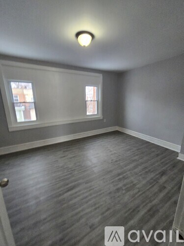 A room with grey walls and wooden flooring, with a window and a door visible.