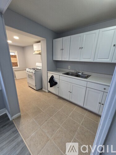 A kitchen with white cabinets and a tiled floor.