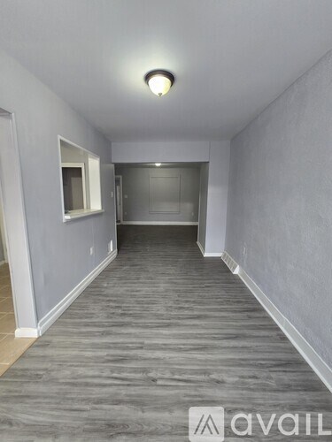A long, narrow room with a grey floor and white walls.