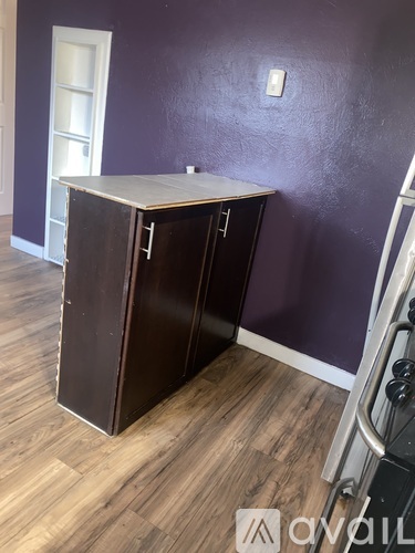 A brown cabinet with a white top is in a room with purple walls.