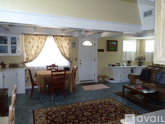 A living room with a brown sofa and a dining table with chairs.